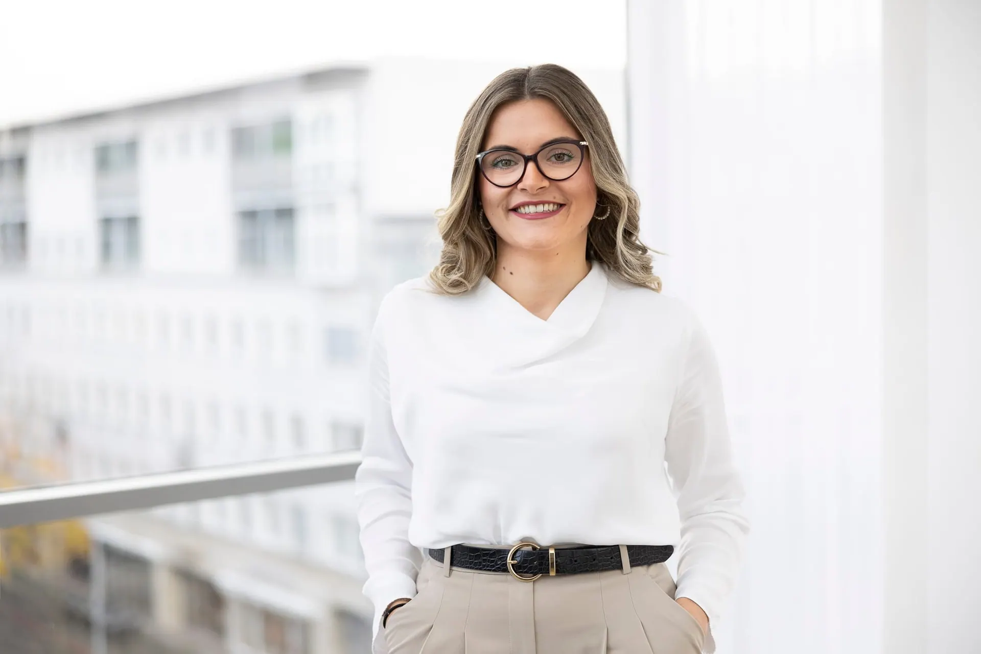 Porträt einer Mitarbeiterin vor dem Bürofenster