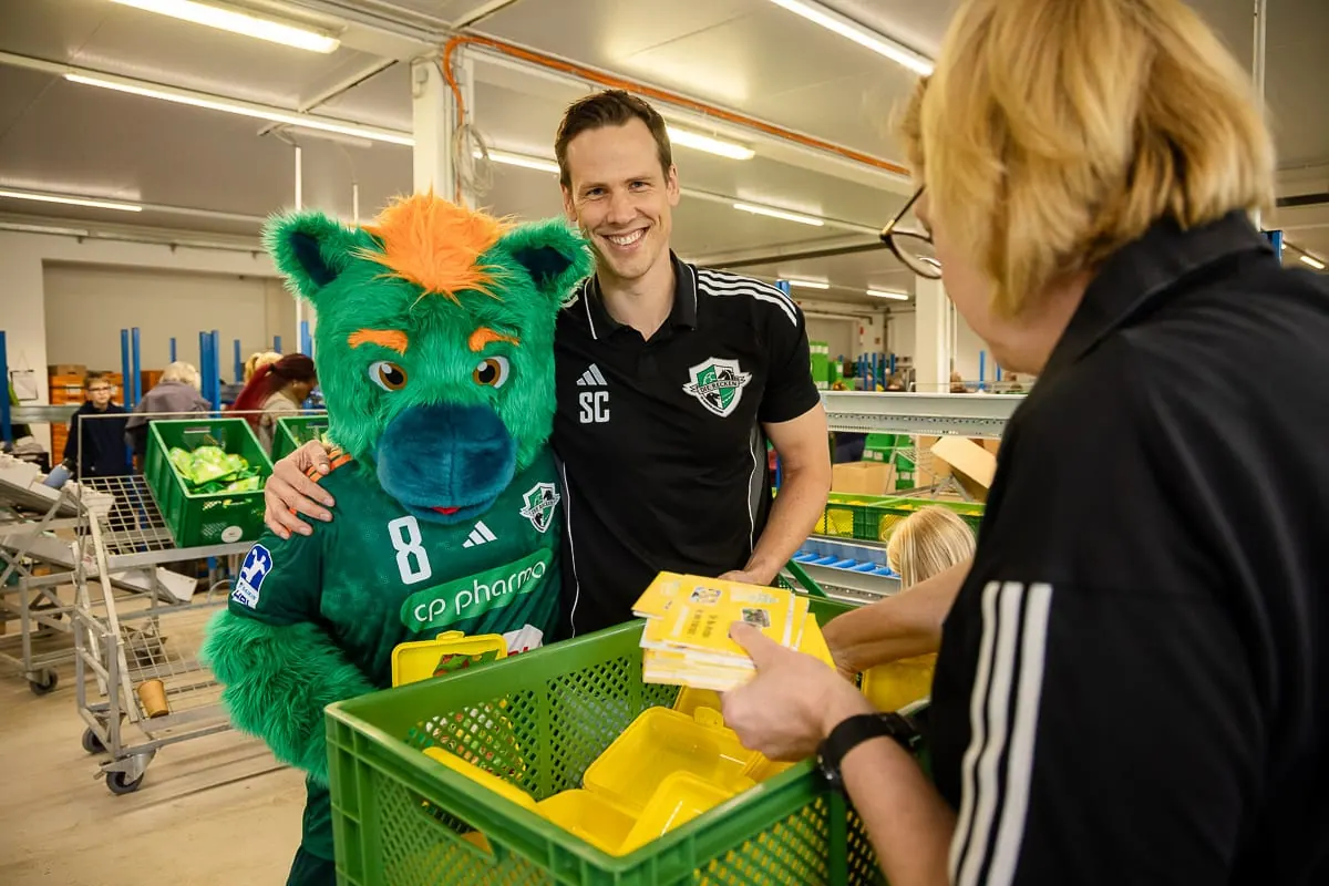 Maskottchen übergibt eine Brotbox an einem Stand
