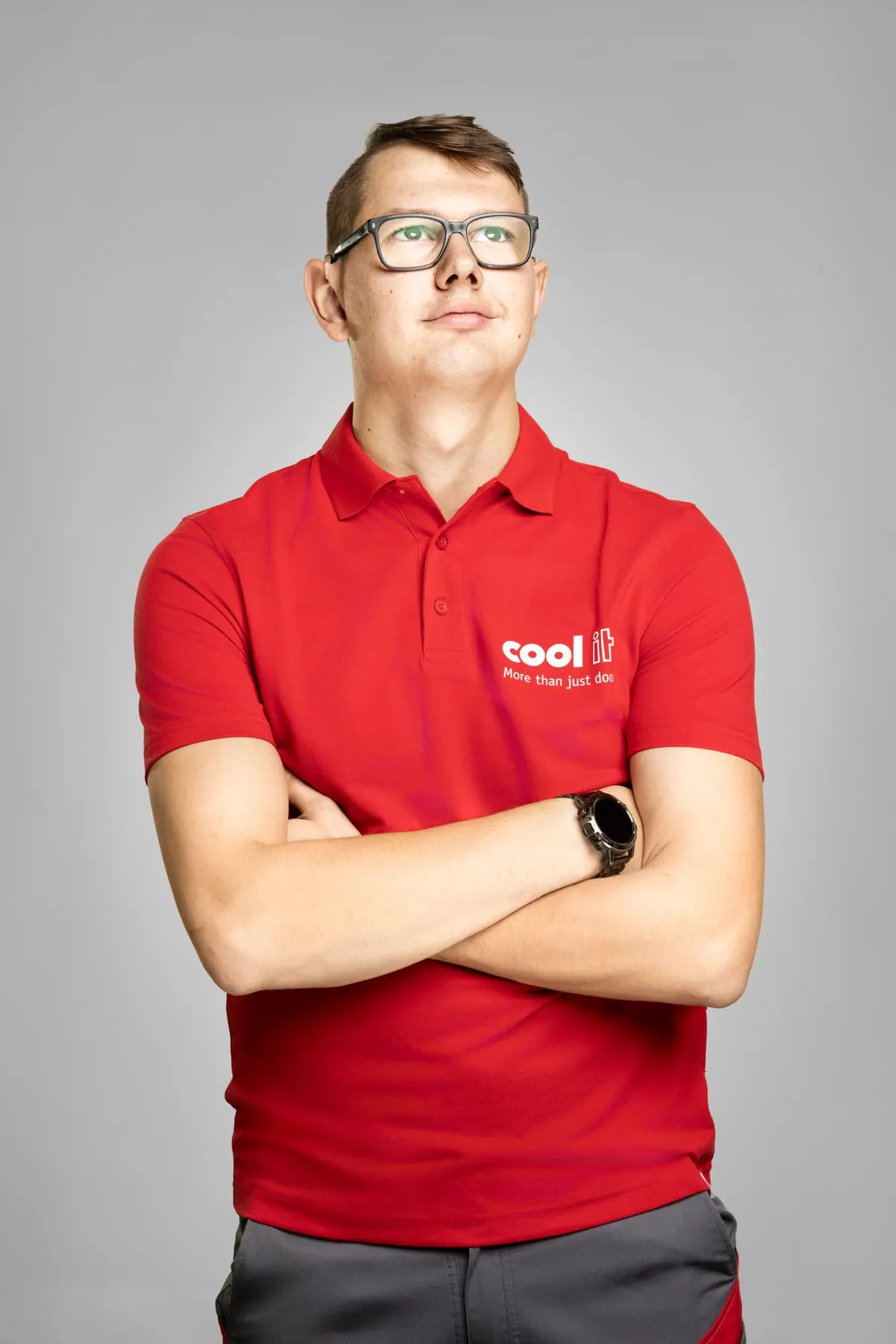 Porträt eines Mitarbeiters im roten Poloshirt vor schwarzem Hintergrund
