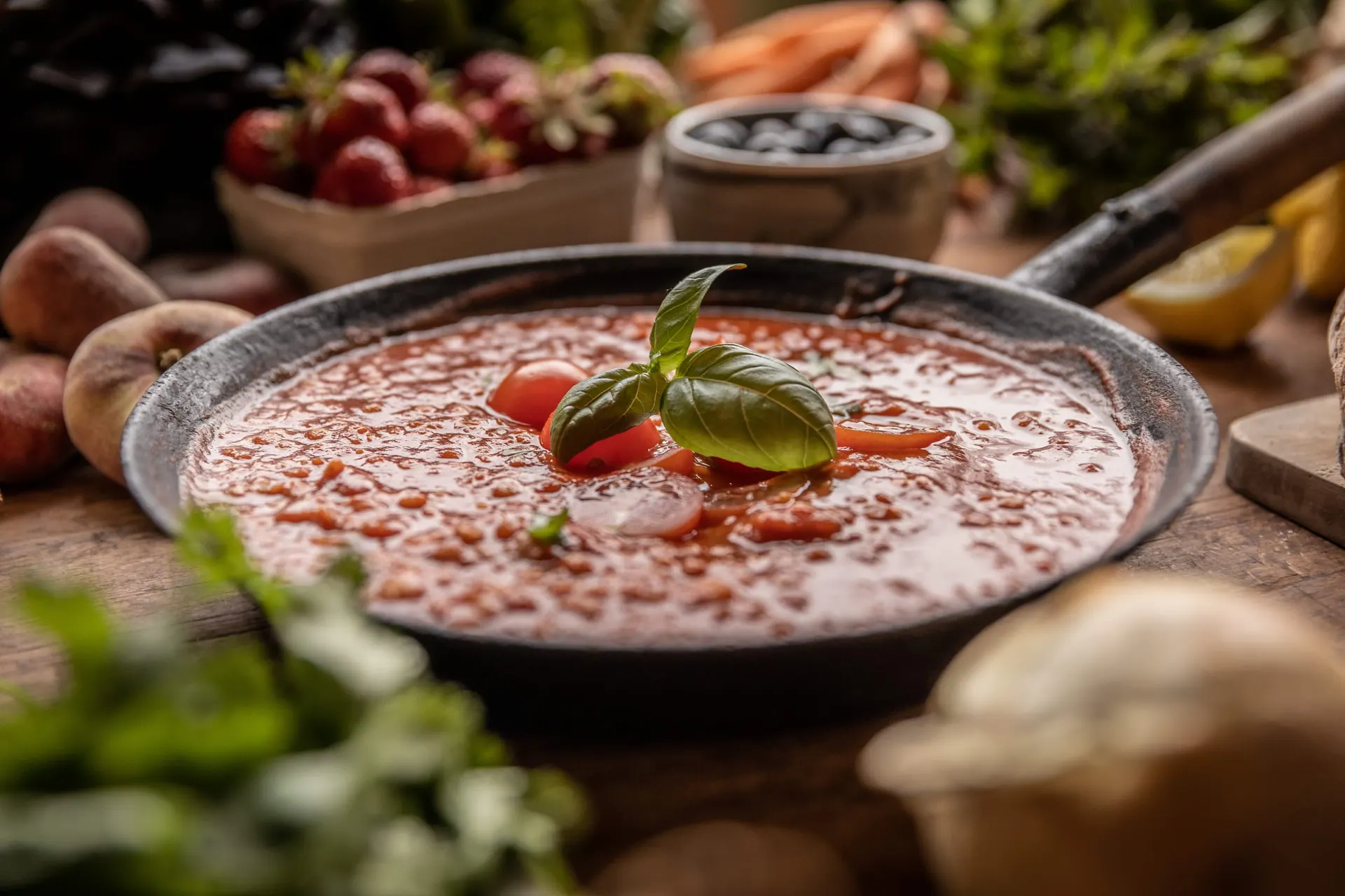 Pfanne mit Tomatensuppe, umgeben von frischem Gemüse