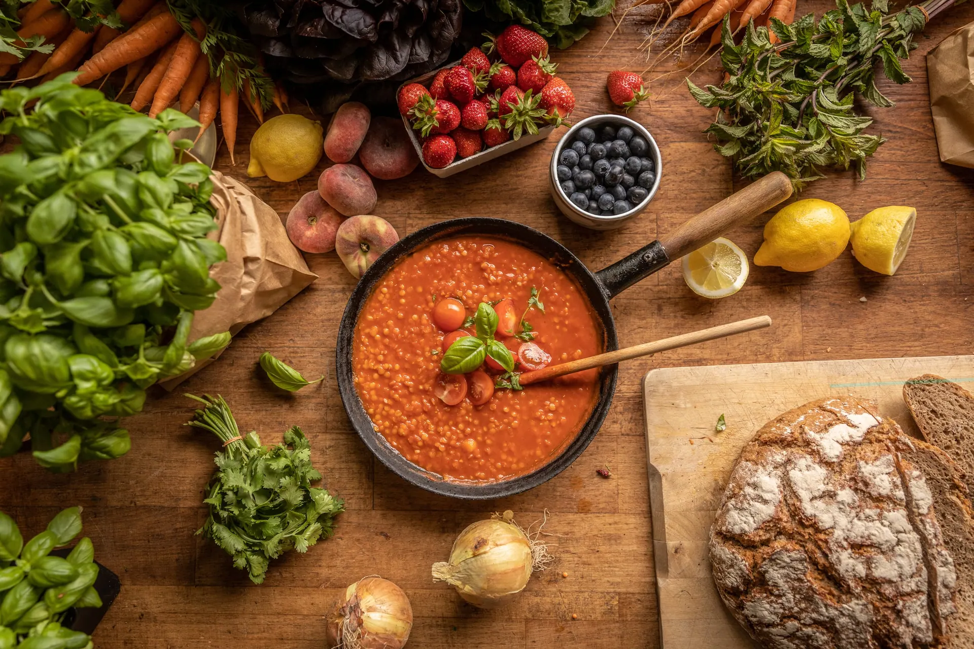 Flatlay aus Gemüse, Beeren, Brot und einer Schüssel Suppe