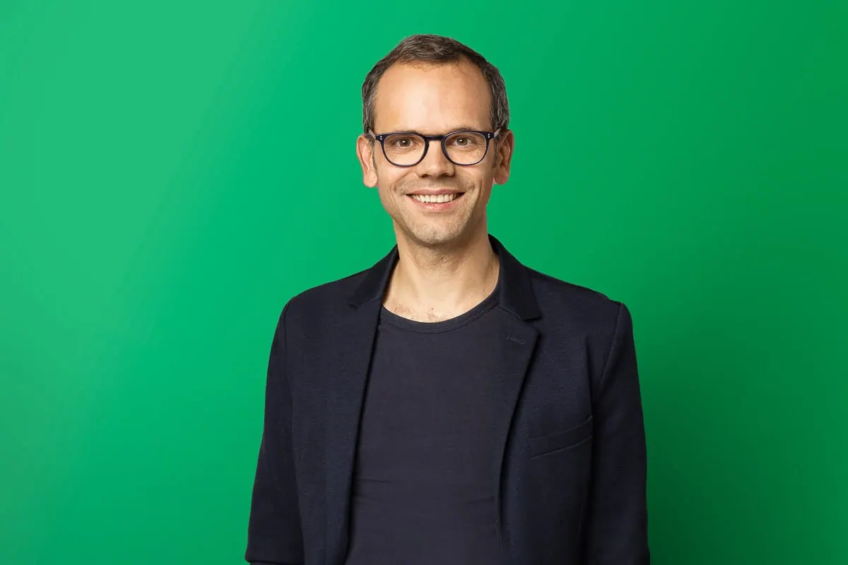 Kandidat mit Brille vor grünem Hintergrund