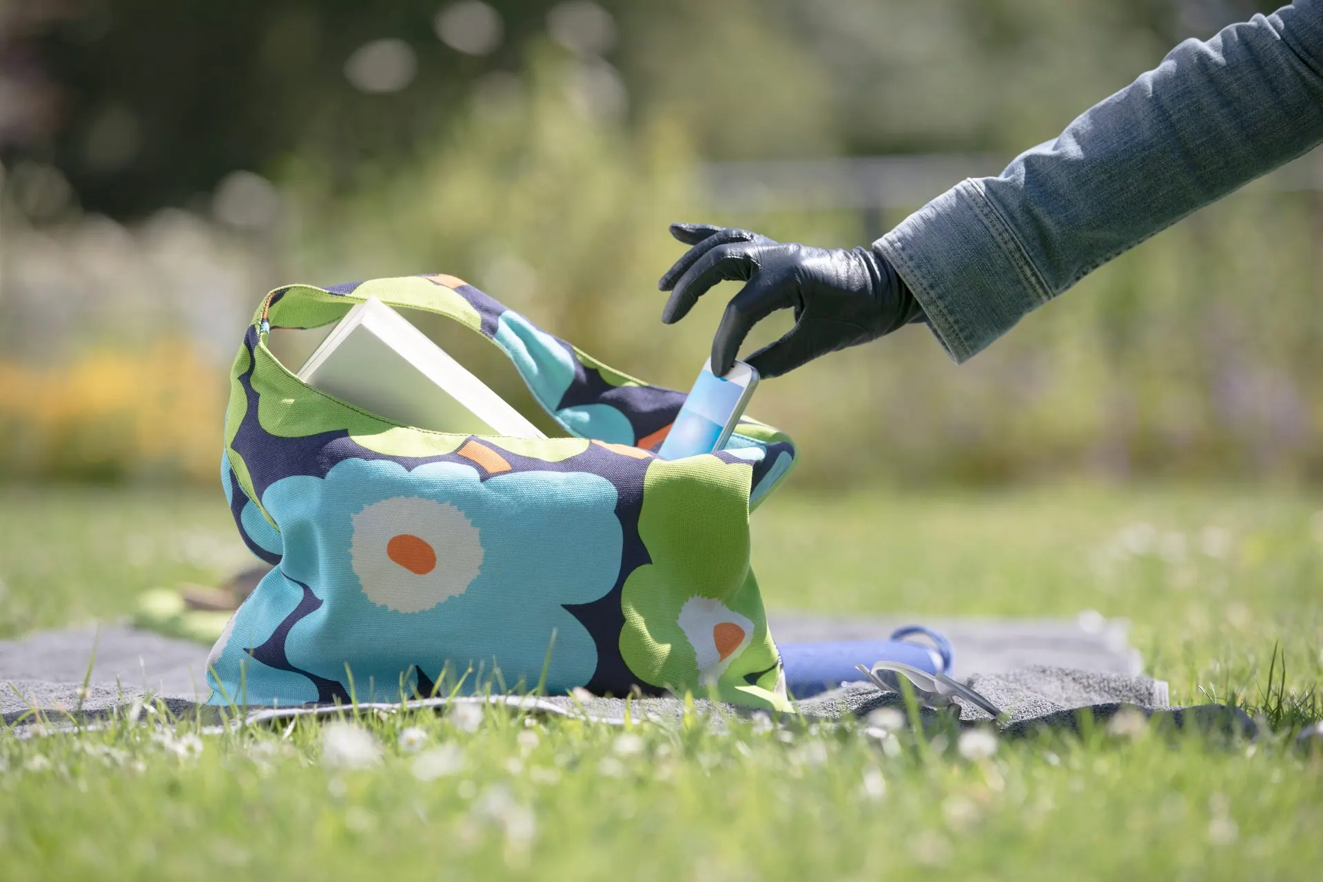 Behandschuhte Hand greift in eine Strandtasche auf der Liegewiese