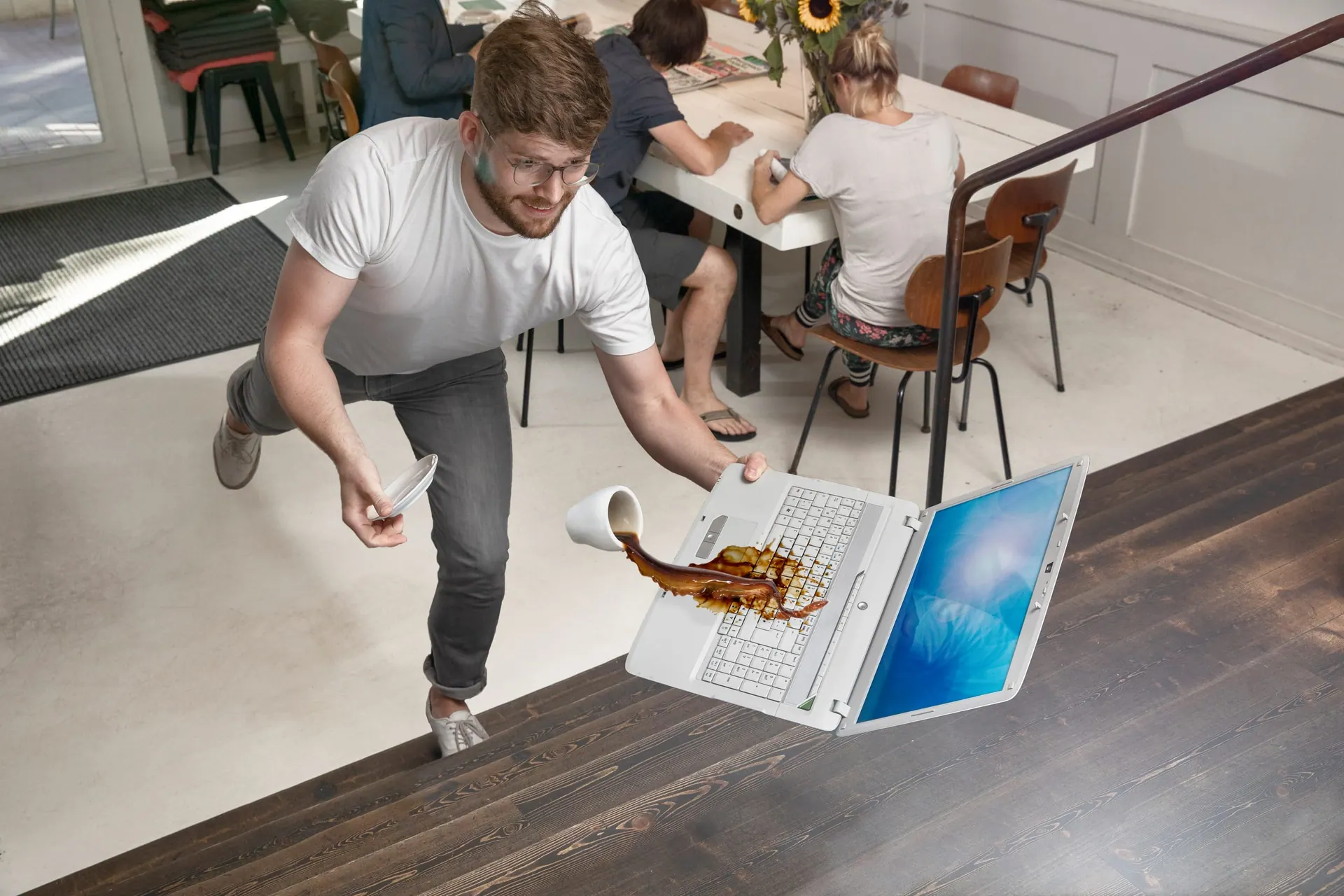Umgestoßenes Glas neben einem Laptop auf einem Tisch