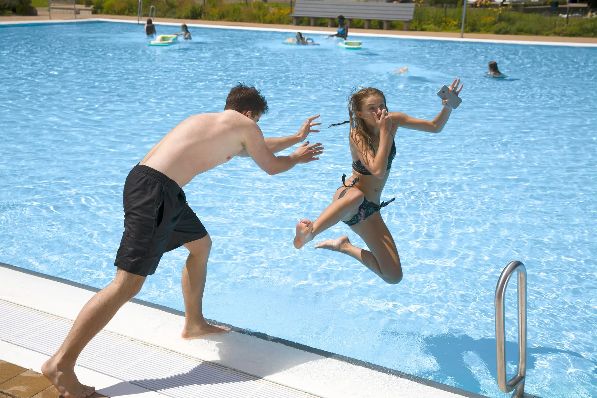 Zwei Menschen springen ins Freibadbecken