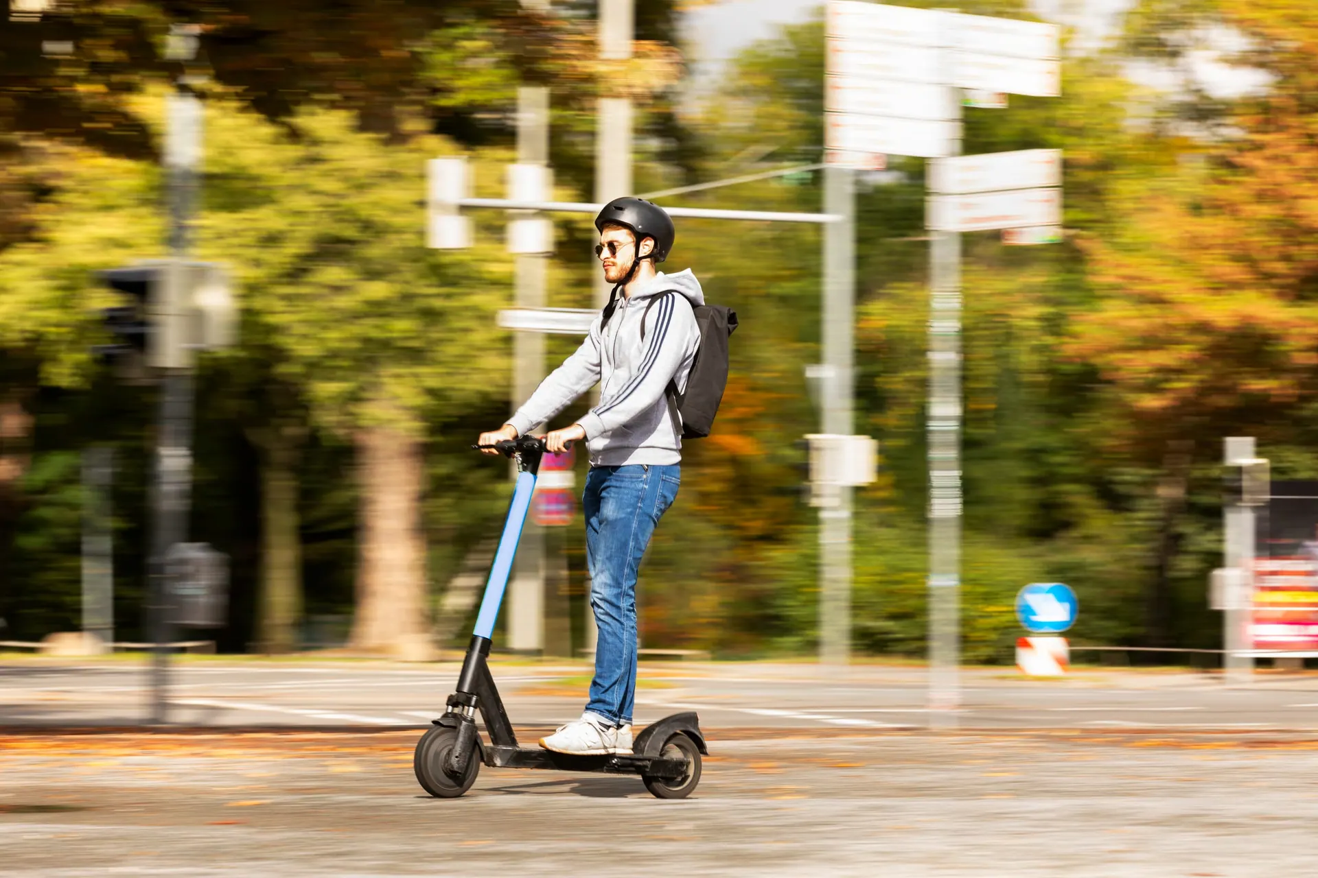 E-Scooter-Fahrt vor herbstlichem Baumbestand
