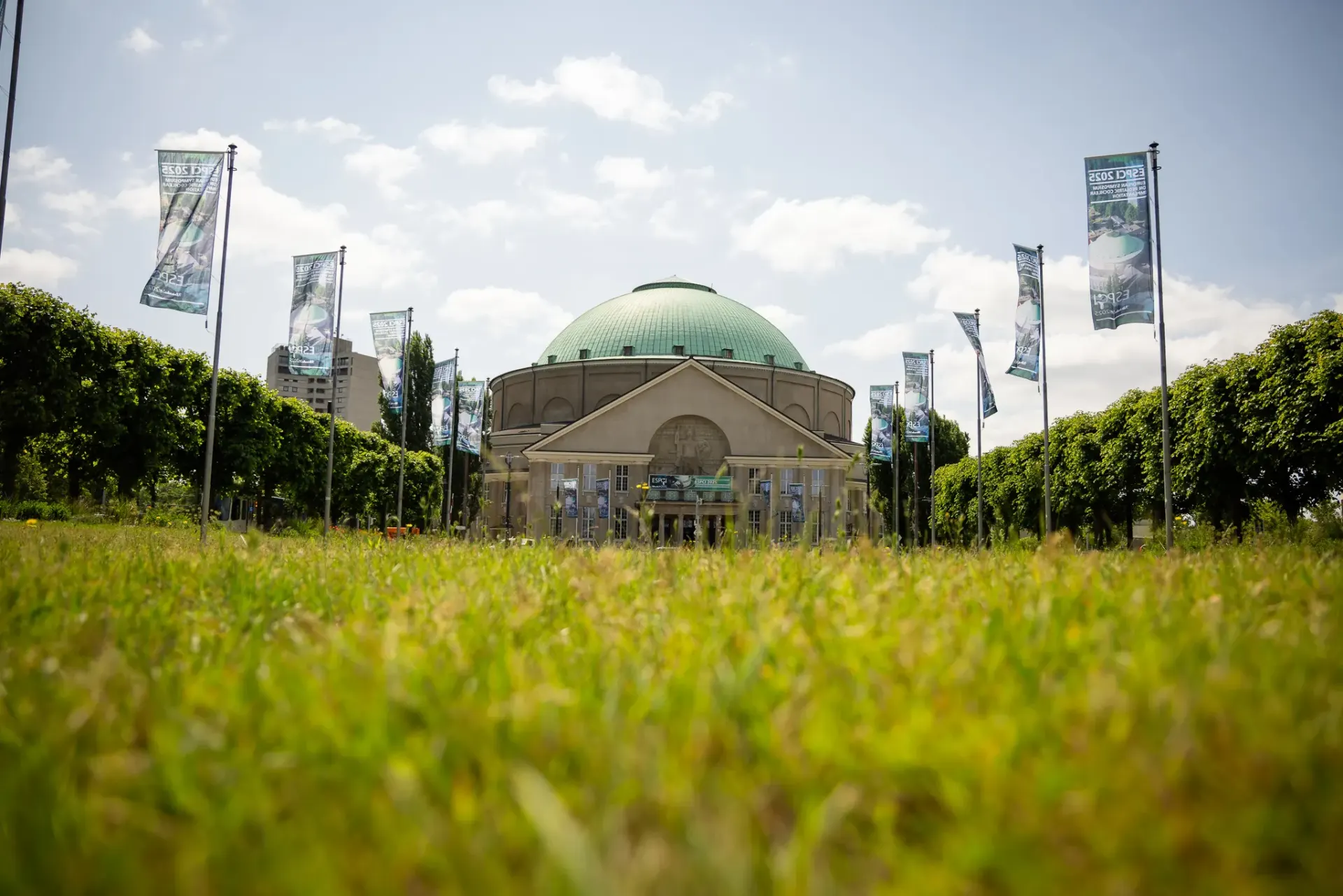 Altes Eingangsportal des Hannover Congress Centrum HCC mit wehenden Fahnen und Wiese im Vordergrund